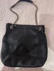 The exterior of the bag is black, with silver hardware accents, while the interior is lined with black fabric. It is...