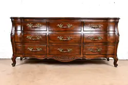 By John Widdicomb. A gorgeous French Provincial Louis XV style carved walnut bombay form long dresser. Solid carved...