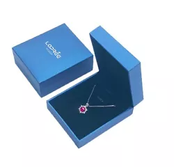 Il arbore en son centre une seule pierre rouge ronde encerclée par une ligne de cristaux blancs brillants sertis...