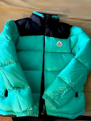 This Moncler Amalteas puffer jacket in teal green is a must-have for any stylish mans wardrobe. Made with high-quality...