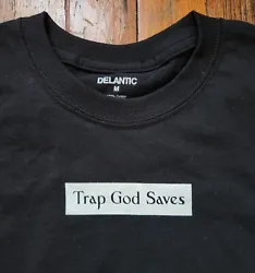 Black cotton shirt has TRAP GOD SAVES graphic silkscreened in white on front. Plain back.