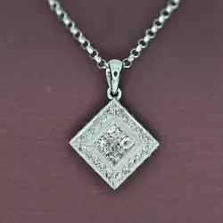 Four princess cut diamonds are invisibly set in the center to give the appearance of a larger diamond. Surrounded by...