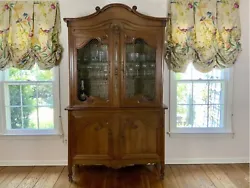 The upper section features a carved arched crest and scrollwork above two cabinet doors with pressed crimped wire inset...
