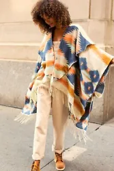 Make a statement in this oversized draped poncho featured in a bold, western-inspired colorful print with fringe ends...