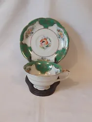 This two-piece teacup and saucer set from Japan features a stunning hand-painted floral design with green border. The...
