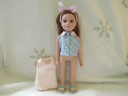 You get the Brunette with Brown Eyes doll wearing a blue shirt, sandals and headband. Also included is the extra shirt...