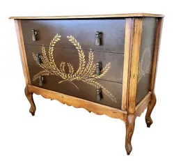 A two-tone wheat stencil designed three drawer dresser with metal tassel stylized drawer pulls that was purchased at...