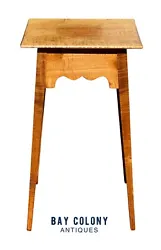 The table has a square top with a scalloped apron and splayed legs. The darker circle at the center of the top is the...